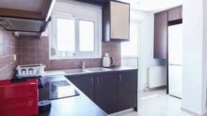 A modern kitchen with dark cabinets, a red appliance, and a window above the sink. - Gorgeous Apt w Magical View GC 3332-02 (Athens)