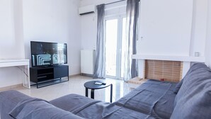 A modern living room with a grey sofa, a black entertainment unit, and a flat-screen TV. - Gorgeous Apt w Magical View GC 3332-02 (Athens)