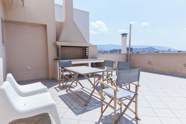An outdoor patio with a grill, a table, and chairs.