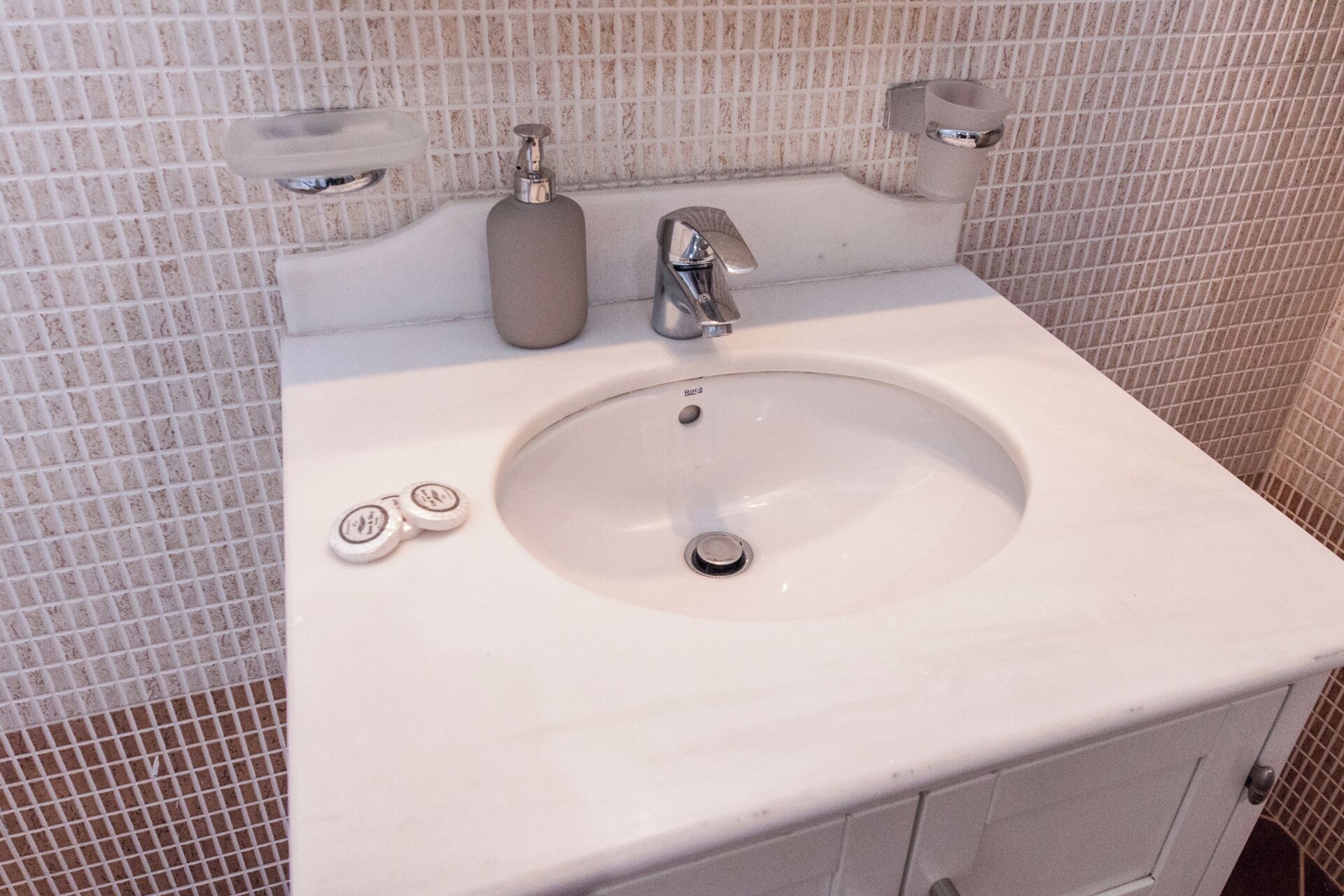A bathroom sink with a mirror above it, a faucet, and two soap dispensers.
