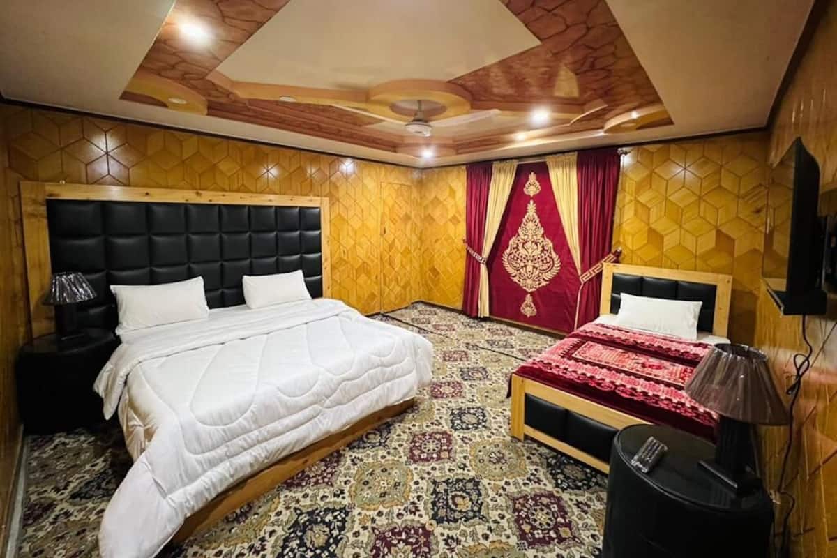 Ein Schlafzimmer mit einem großen Bett, zwei Nachttischen, einer Deckenleuchte und einem gemusterten Teppich.