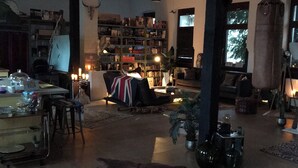 A spacious living room with a high ceiling, a large bookshelf, and a cozy seating area. - Unique yoga loft! Quiet room for courses, seminars, workshops! (Sinsheim)
