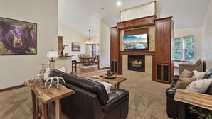 Amplia sala de estar con chimenea, sofá de cuero y televisor.