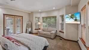 Un dormitorio con cama, ventilador de techo, televisión y ventana con persianas.