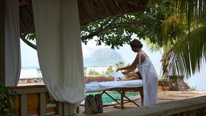 En massagebehandling i en tropisk miljö med utsikt över havet och bergen.