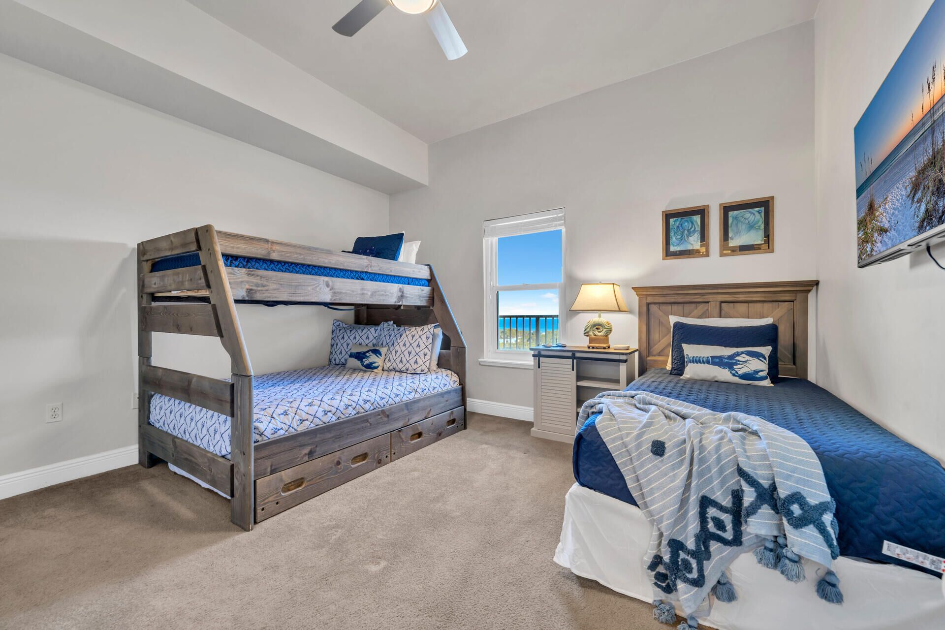 A bedroom with a bunk bed, a single bed, a desk, and a window with a view.