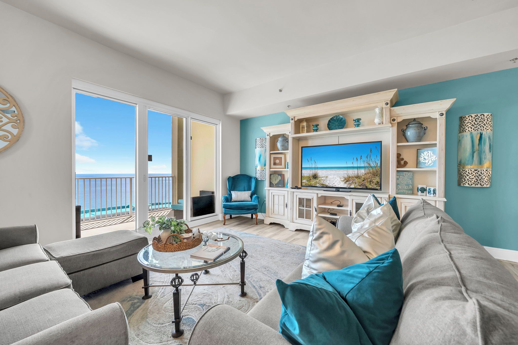 A living room with a TV, sofa, and a view of the ocean.