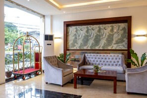 A lobby with a marble floor, a large abstract painting, two sofas, a coffee table, and a cart. - Kojo Hotels Cebu -Mandaue (Mandaue)
