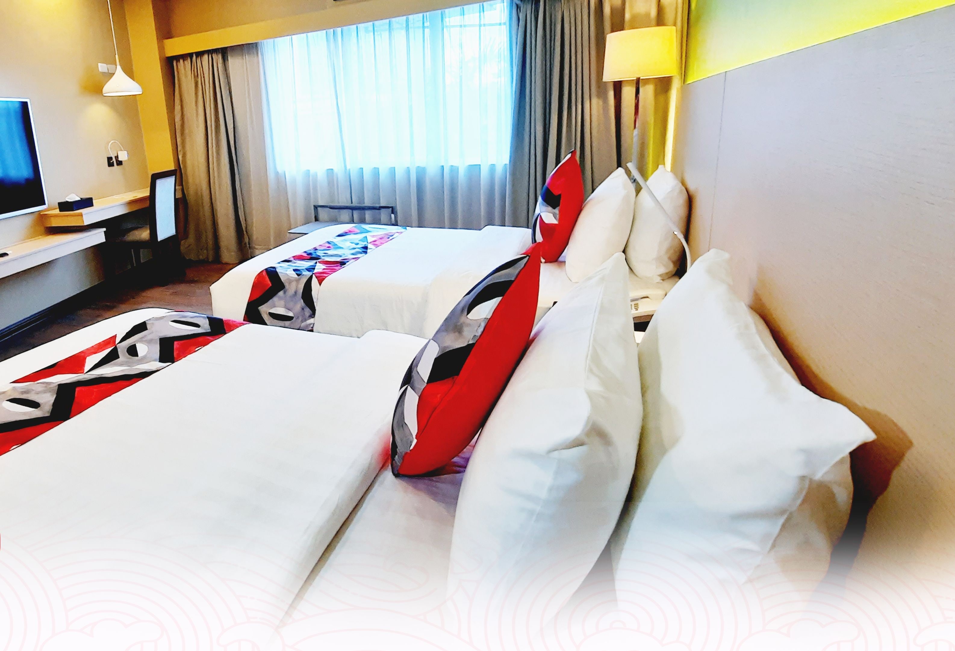 A hotel room with two beds, a TV, and a desk.