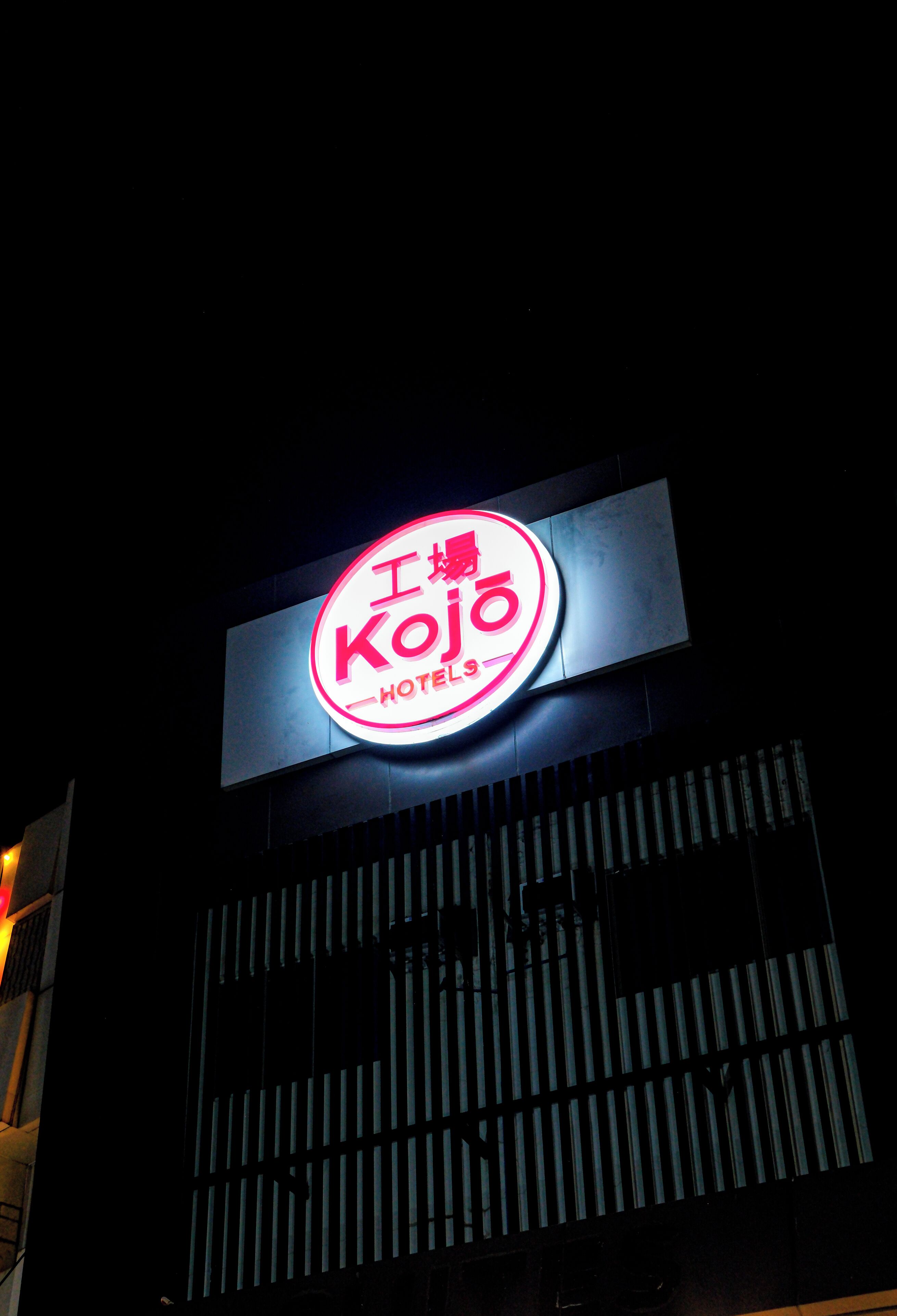 A hotel sign with the name "Kojo Hotels" illuminated in red.