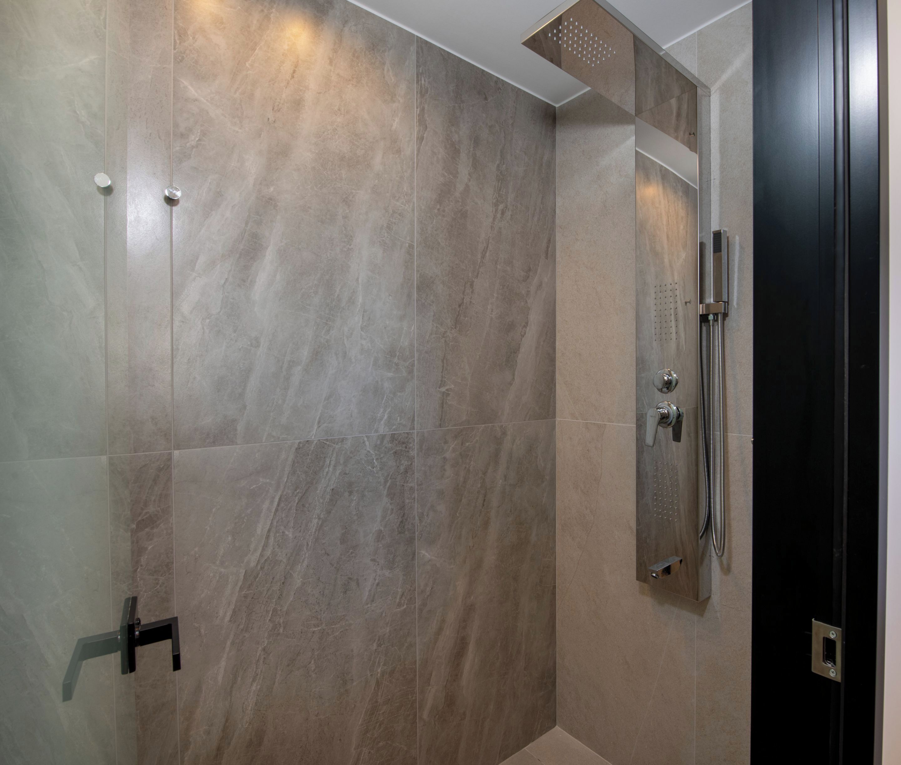 Une douche moderne dotée d’un pommeau de douche à main et d’un panneau de commande fixé au mur.