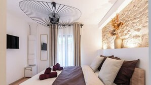 Ett modernt hotellrum med en stor säng, en unik taklampa, en platt-TV och en dekorativ väggdekoration.
