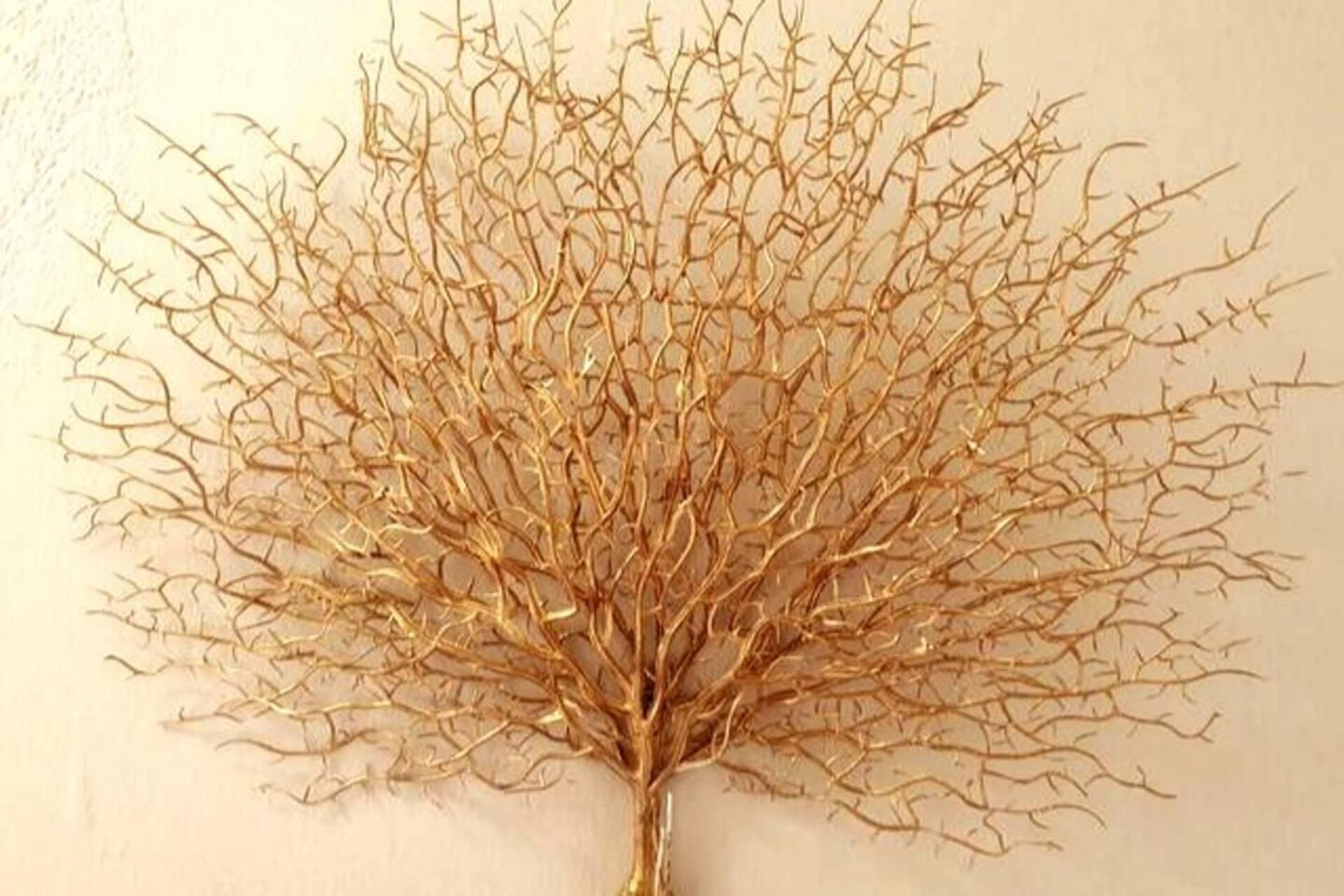 Una obra de arte mural dorada y detallada que representa un árbol con una estructura de ramas complejas.