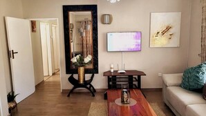Un salon avec une table basse en bois, un canapé, un téléviseur et un grand miroir.