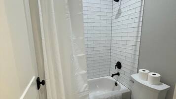 Un baño con una bañera blanca, inodoro y cortina de ducha.