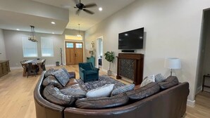 A spacious living room with a large sectional sofa, a dining area, and a fireplace.