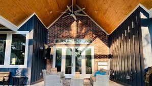 A covered patio area with wicker furniture and a brick fireplace.