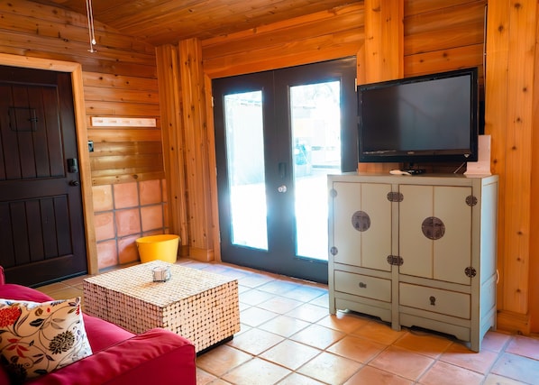 A cozy cabin interior with a wooden interior, a television on a cabinet, a red sofa, and a small table. - Sargent, Tx Spacious, Creekfront Home, Amazing Outdoor Space & 2 Fishing Piers. (Sargent)