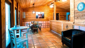 Et træindrettet interiør med et spiseområde, en bar og en sort læderstol.