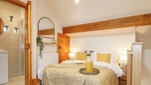 A bedroom with a wooden ceiling, a bed with white bedding, a bedside table with a lamp, and a small plant on the wall. - Brightside (Matlock)