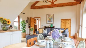 A dining area with a table set for four, surrounded by wooden chairs. A large window provides natural light, and a wooden ceiling with exposed beams is visible. - Brightside (Matlock)