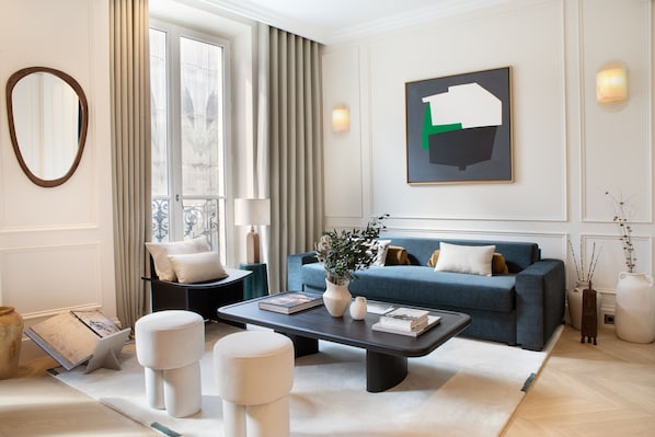 Relax in this stylish living room with a blue sofa, dark coffee table, and a beautiful abstract painting.