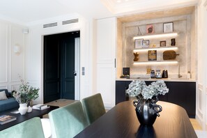 Enjoy meals in the dining area with a dark table and green chairs, surrounded by artwork and decorative pieces.