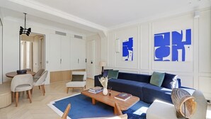 Una sala de estar moderna con un sofá azul, una mesa de centro y un comedor con sillas y una mesa.
