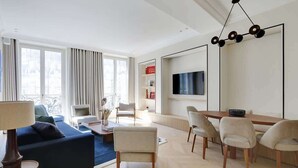 Una sala de estar moderna con sofá, sillas, una mesa de comedor y una televisión.