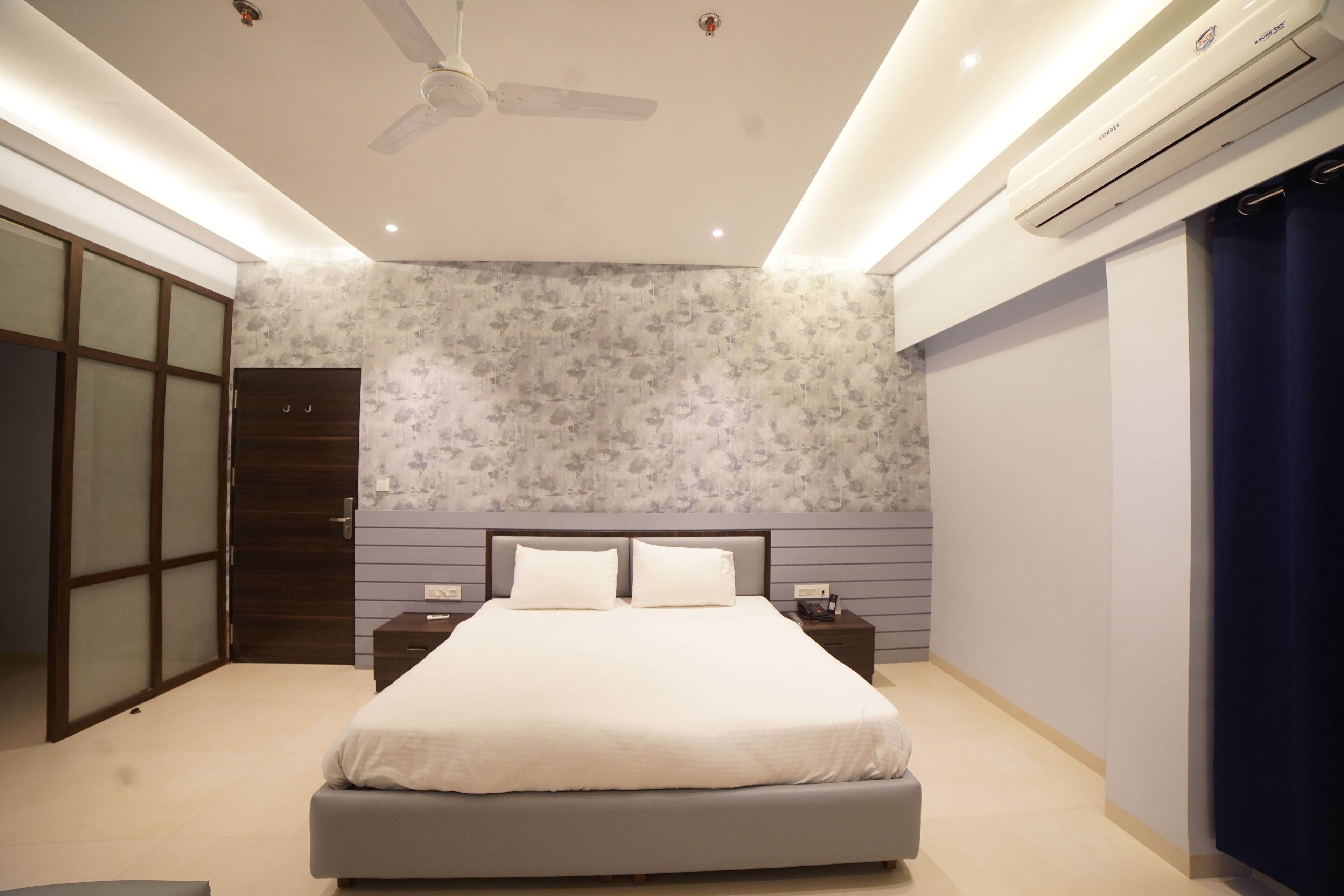Une chambre moderne avec un grand lit, un ventilateur de plafond et un appareil de climatisation.