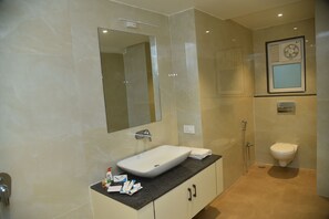 A modern bathroom with a large mirror, a white sink, and a toilet. - HOTEL MAYUR (Rajnandgaon)