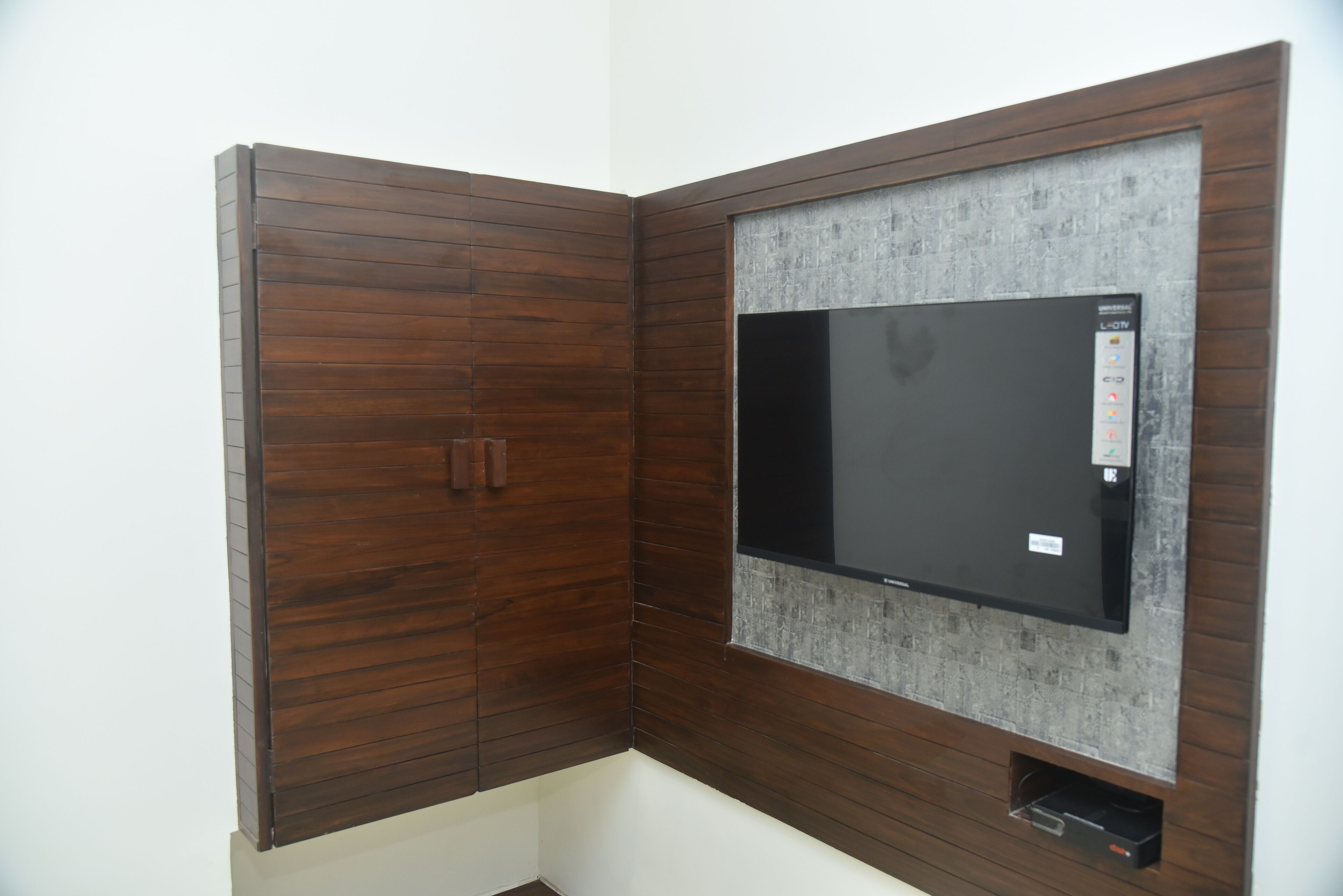 A room with a built-in TV on a brick wall, wooden paneling, and a small storage compartment below.