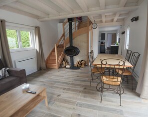 Cozy living area with a high ceiling, black wood-burning stove, and dining table for meals and gatherings.