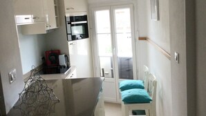 Eine Küche mit weißen Schränken, einer Uhr und einem Fenster.