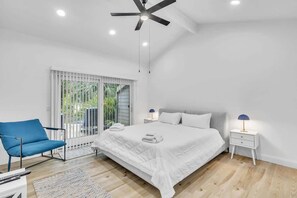 Une chambre à coucher comprenant un lit, une chaise, une table de chevet et un ventilateur de plafond.