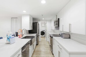 Une cuisine moderne équipée d’appareils électroménagers en acier inoxydable, d’un lave-linge et d’un grille-pain.