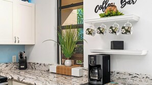 A kitchen with a coffee machine, a plant, and a sign that reads "Coffee Bar". - Summer Deal Oceanfront Kona Condo with Sunset Views and Resort Pool (Kailua Kona)