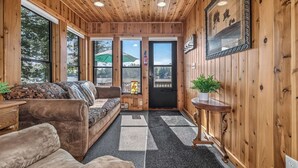 Un intérieur en bois avec un canapé, une petite table et une porte donnant sur l’extérieur.