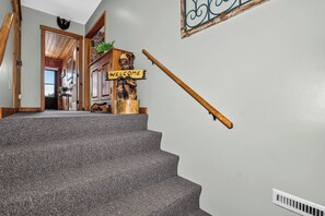 A staircase with a 'WELCOME' sign, a wooden handrail, and a wall-mounted sign with a design.