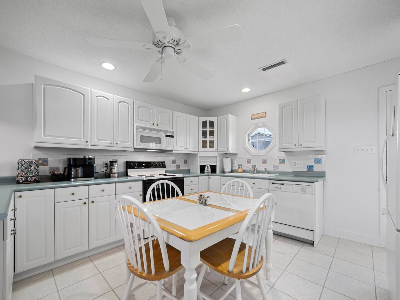 A kitchen with white cabinets, a wooden dining table, and chairs.