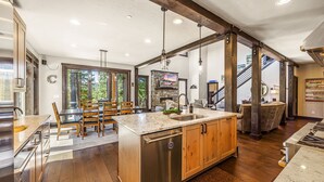 Une cuisine spacieuse dotée d’un grand îlot central, de meubles en bois et d’une cheminée en pierre.