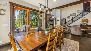 Un vaste espace dédié à la salle à manger, avec une table et des chaises en bois, une cheminée et une vue sur l’extérieur.
