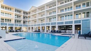 Un hôtel à plusieurs étages doté d’une piscine centrale, de balcons et d’espaces de détente en plein air.