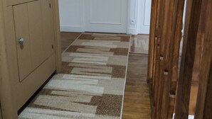 Un pasillo con piso de madera, un armario color beige y dos puertas blancas con letreros que dicen 'Chambre'.