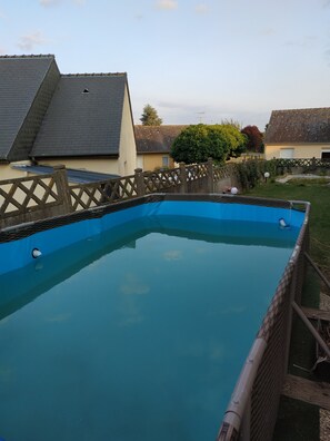 Ein rechteckiger Pool mit Holzzaun und glatter, blauer Wasseroberfläche.
