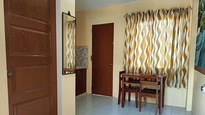 Un pasillo con una puerta de madera, una pequeña mesa con sillas y cortinas estampadas.