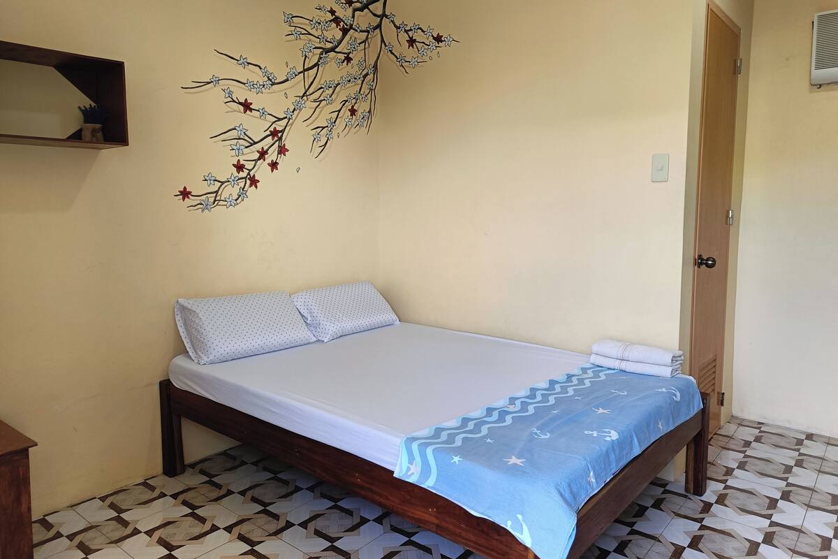Une chambre à coucher avec un lit, une étagère fixée au mur, une porte et des carreaux de sol à motifs.