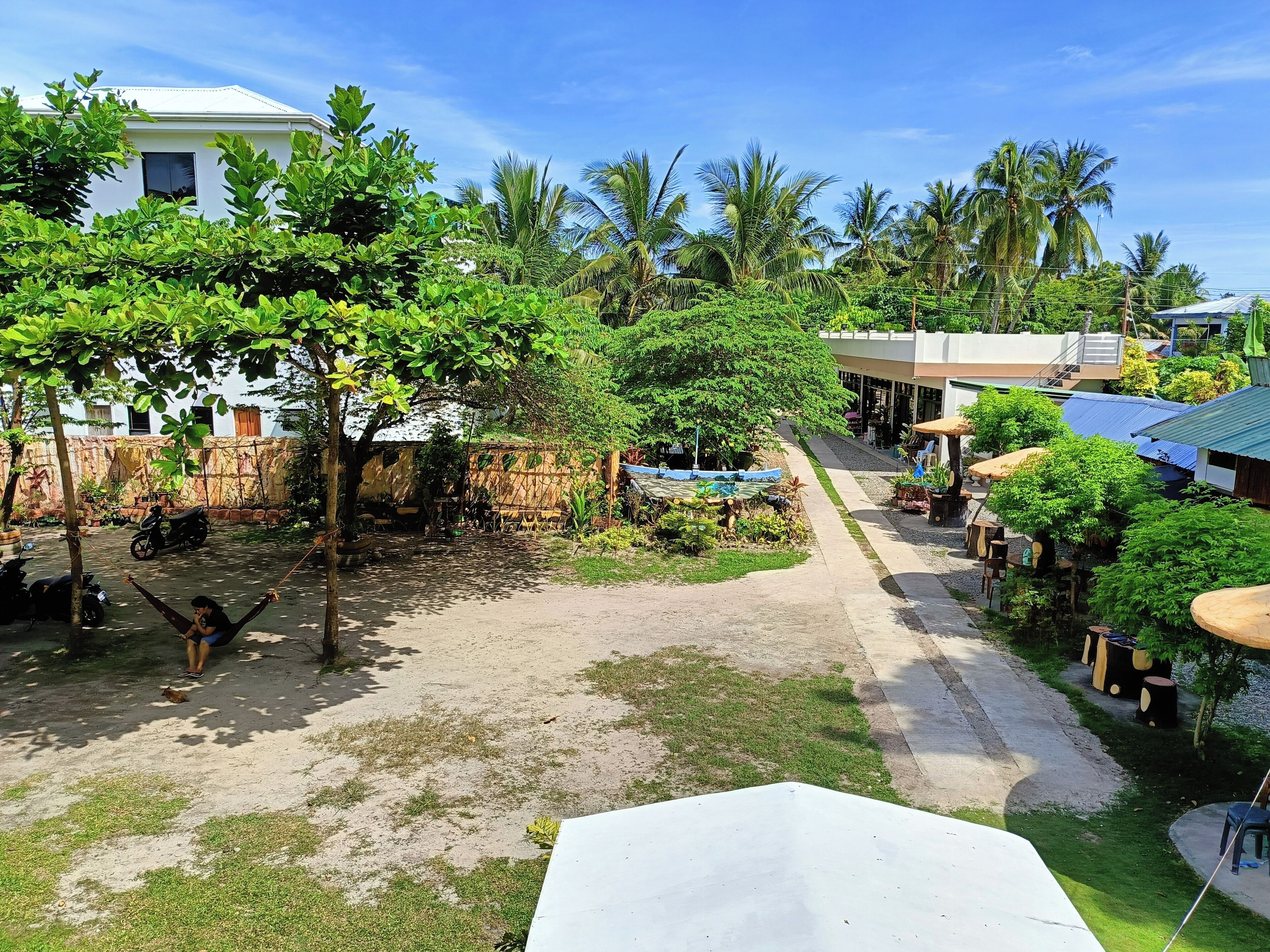 A courtyard with a swing, a scooter, and a pathway leading to a building with a blue roof.