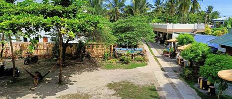 A courtyard with a swing, a scooter, and a pathway leading to a building with a blue roof.