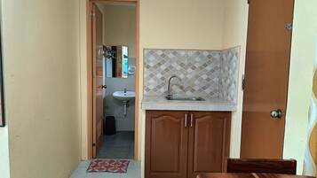 A small kitchen with a sink, wooden cabinets, and a tiled backsplash.